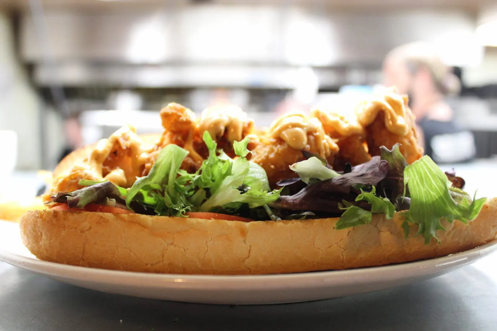Fried shrimp poboy dressed with greens, tomato, and remoulade on a Gambino roll